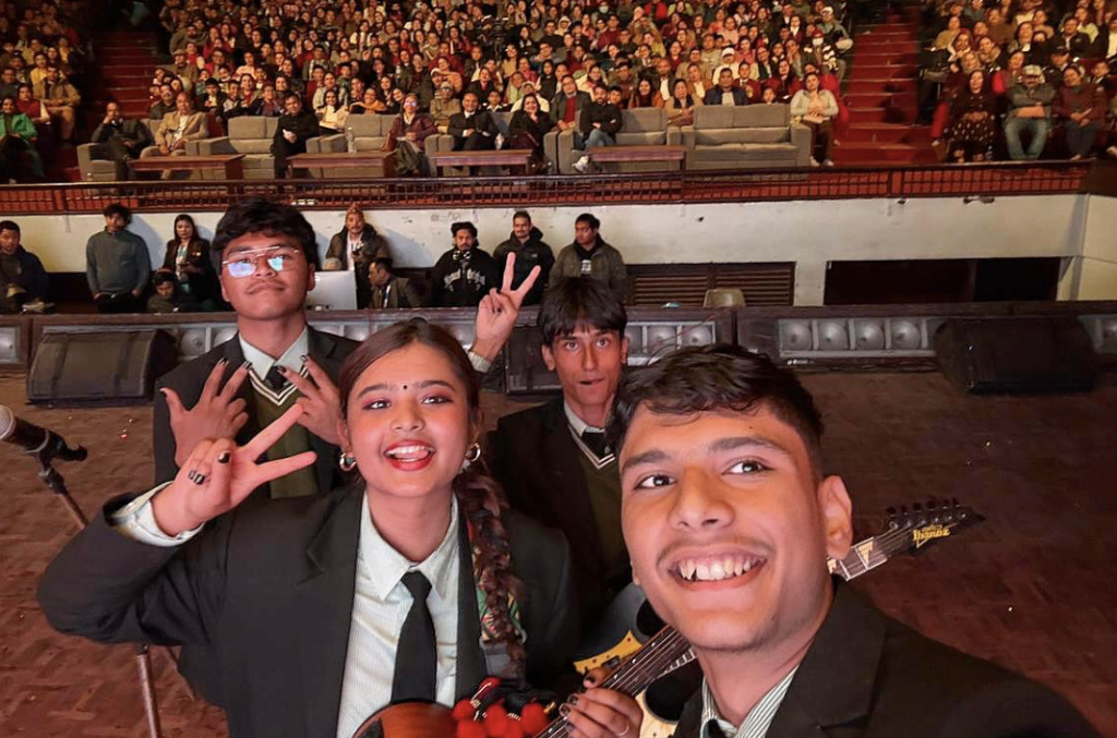 Amrit Raj Pokhrel taking a selfie on stage with his band the_sn4kes, showing the audience in the background.
