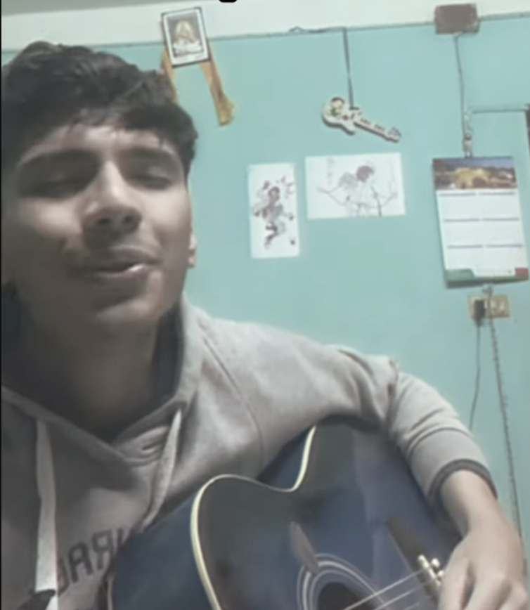 Amrit Raj Pokhrel playing an acoustic guitar during a solo recording session.
